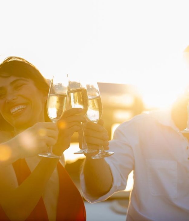 Blurred Group of People man and woman friends enjoy party drinking champagne together while catamaran boat sailing at summer sunset. Male and female relax outdoor lifestyle activity on travel vacation