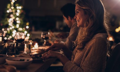 Beautiful woman having christmas dinner with family Beautiful young woman sitting with family and having christmas dinner. Family celebrating christmas together at home.